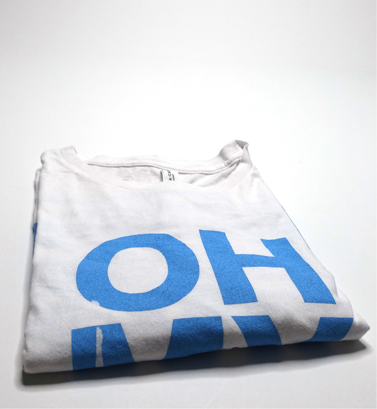 A white long sleeve t-shirt with the text 'OH MY GOD' printed in blue on the front.